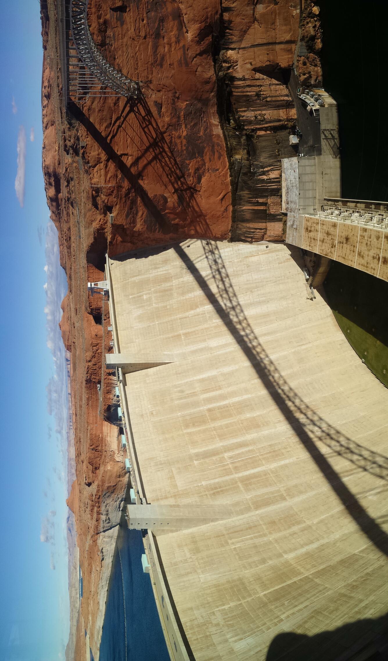 View of Glen Canyon Dam from above on south side, with small corner of Lake Powell in corner