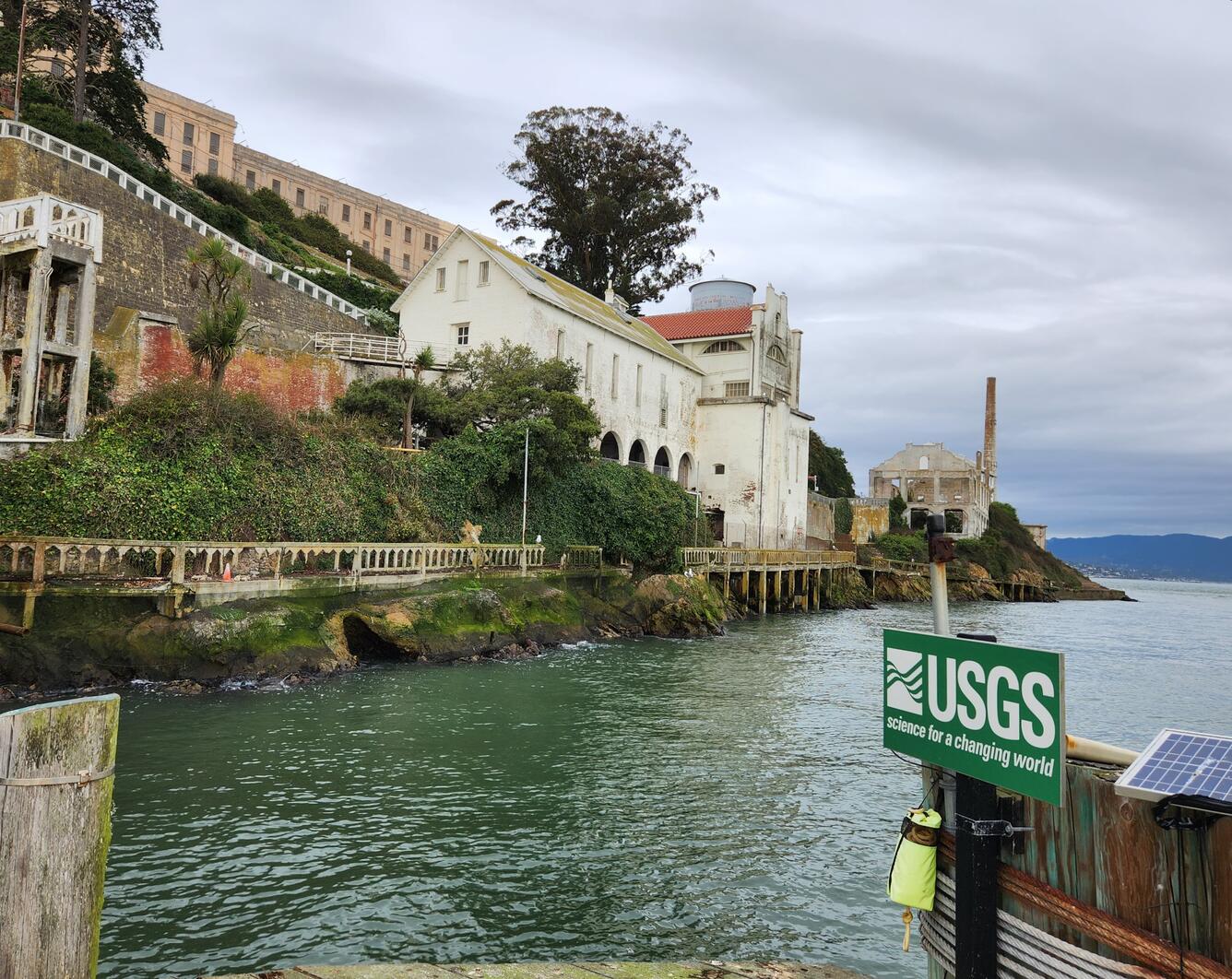 USGS sign on streamgage with historic buildings of Alcatraz in background