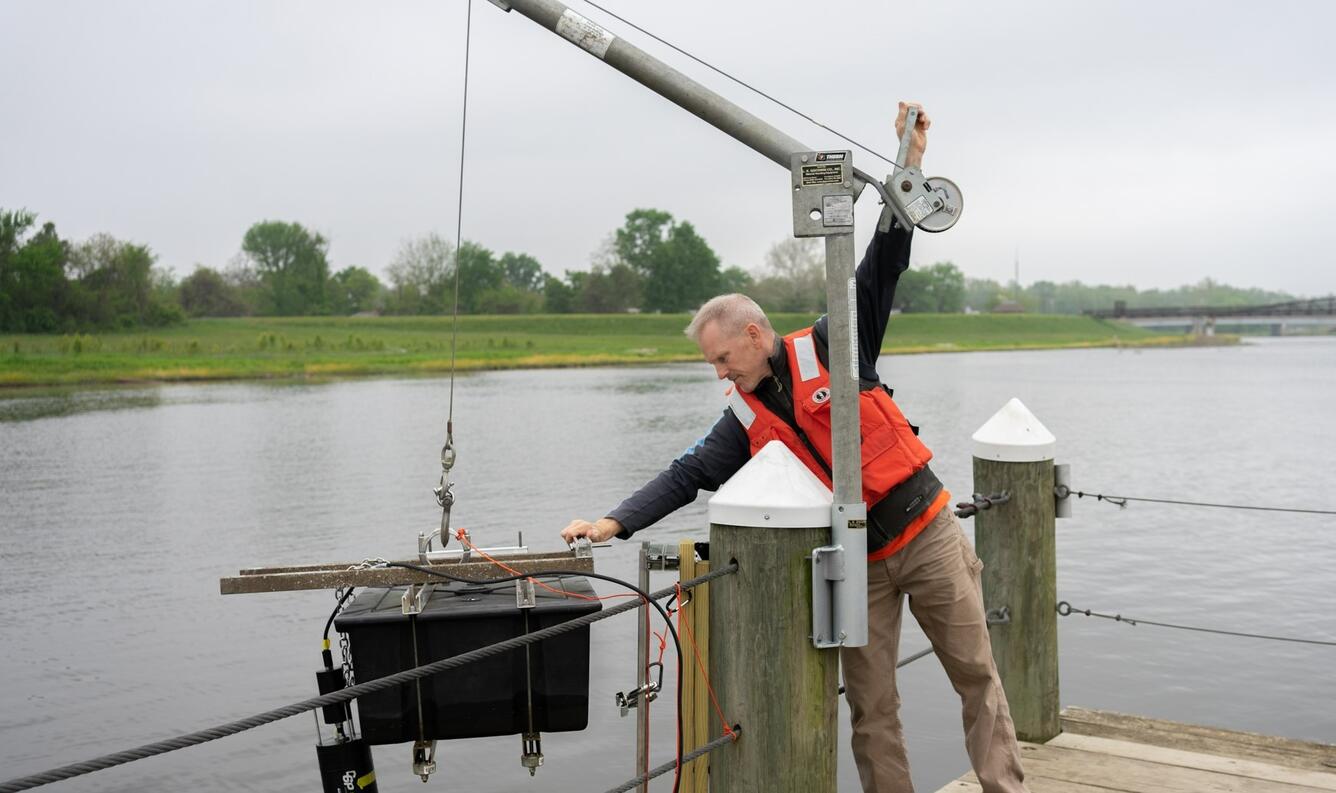 Dave Brower lowers a fluorometer into a river