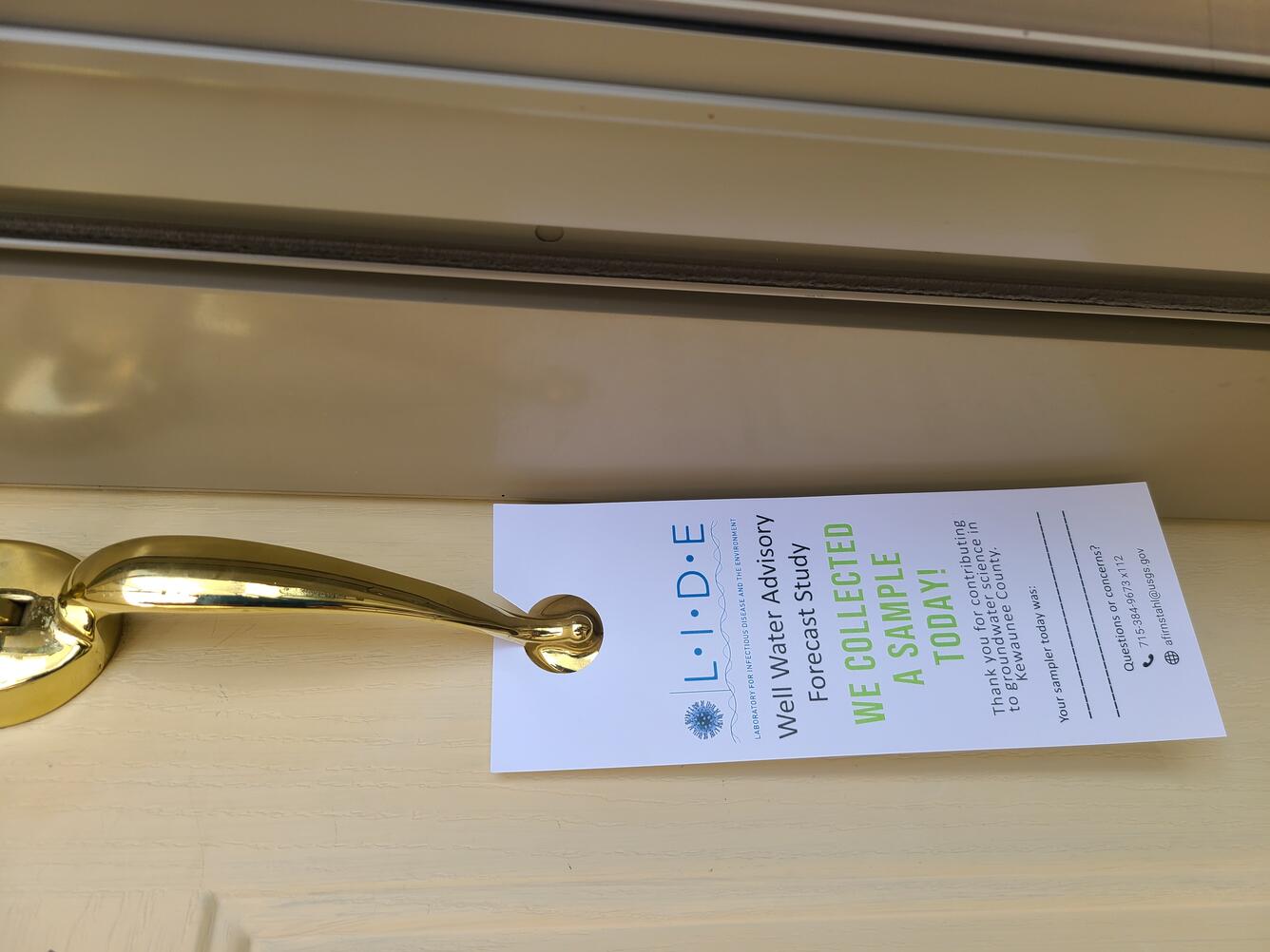 Paper flyer hanging from door handle for a wall water advisory forecast study