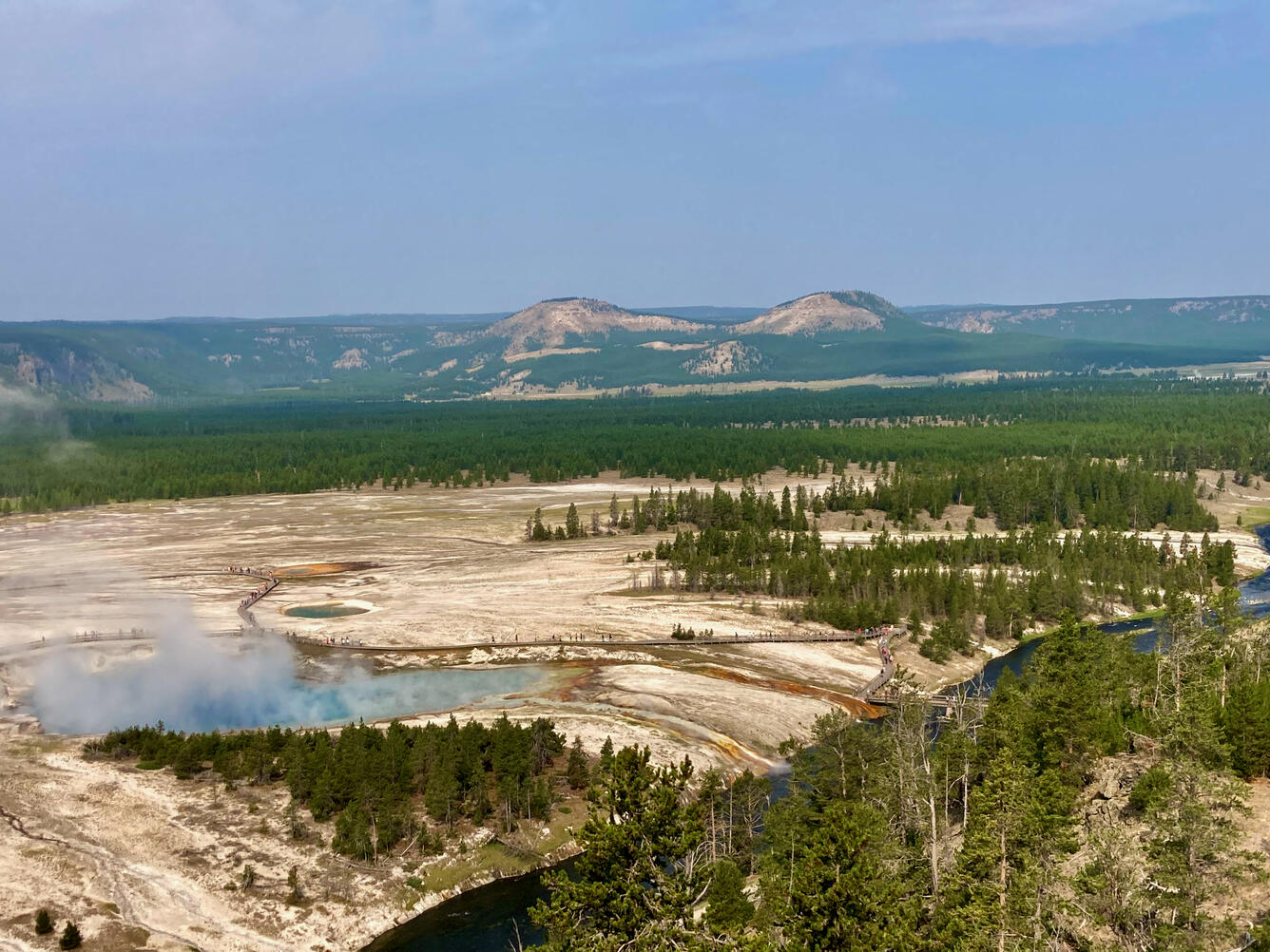 Twin Buttes in Lower Geyser Basin, with Excelsior Geyser of Midway Geyser Basin in the foreground