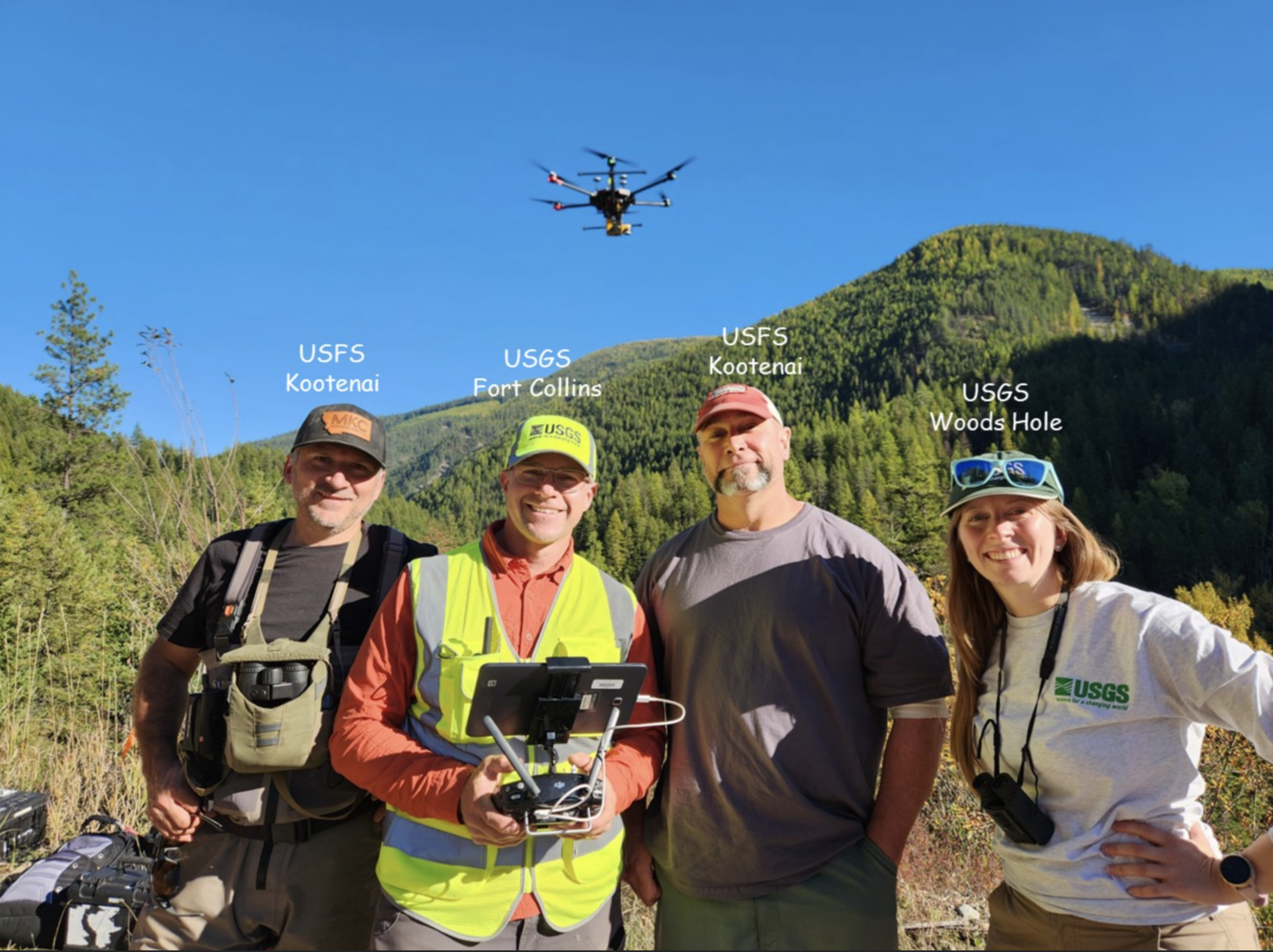 Four people smiling, drone flying overhead