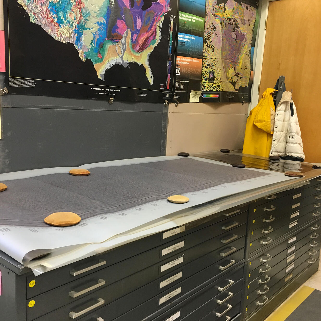 Image shows 35 year old seismic and sampling data being flattened out on a tabletop. 
