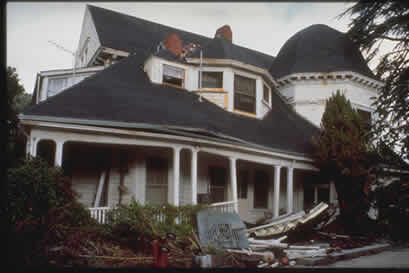 Photo of large house with damage and debris on the ground