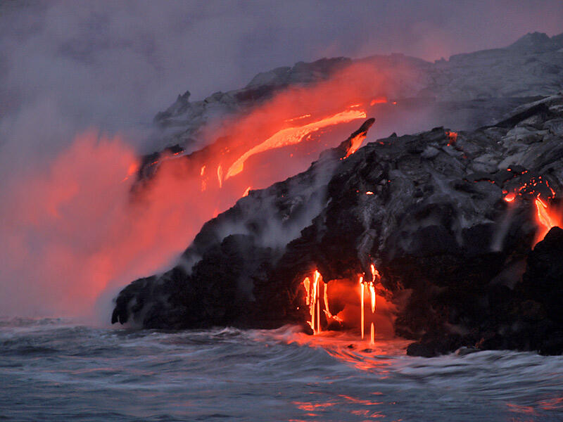 This is a photo of multiple lava falls dropping into the sea, as cascade above remains active.