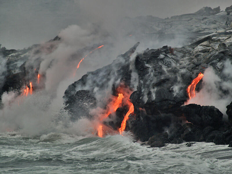 This is a photo of lava flow or cascades, mostly hidden by steam, and multiple lava falls (awash by wave surge).