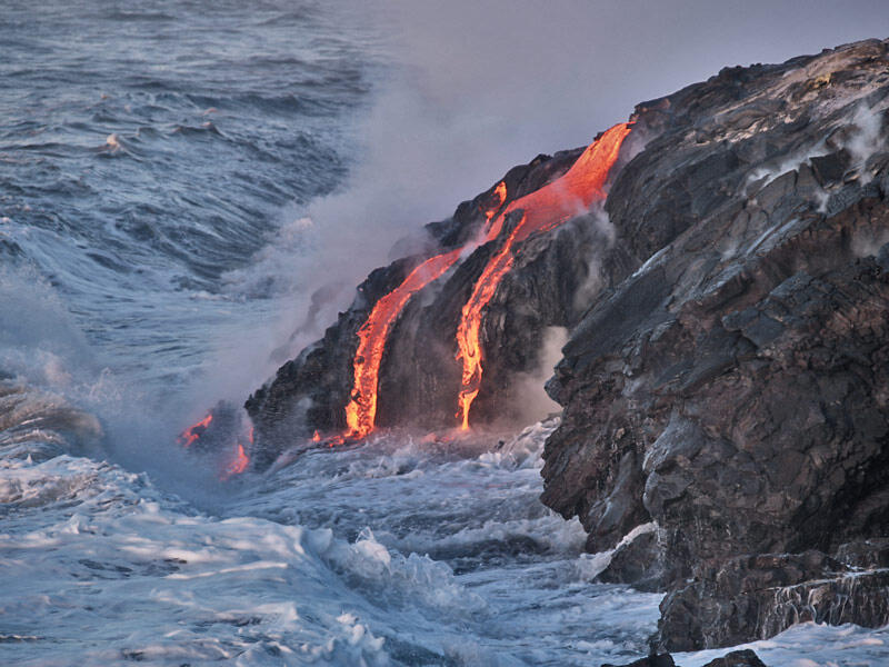 This is a photo of two lava streams dropping into swash, and a third is about to be engulfed by a wave.