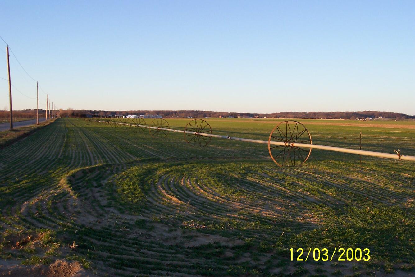 photo of wheel type irrigation rig on green field
