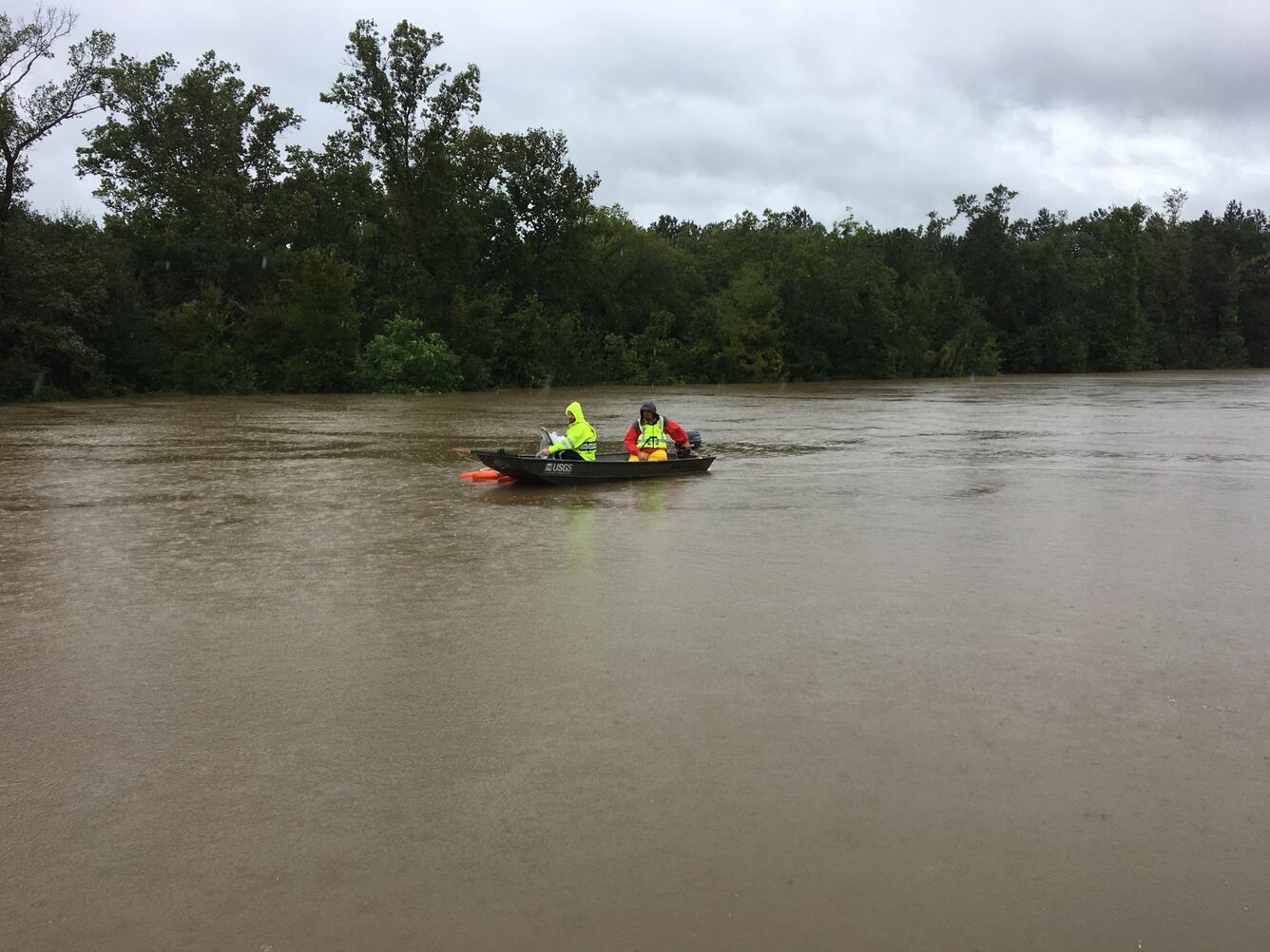 Two USGS technicians boating along a flooded river