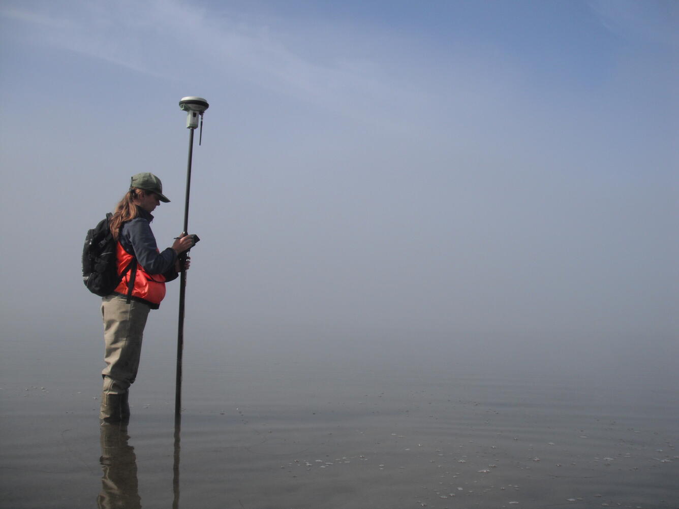 A photo of a USGS researcher measuring elevation in a wetland.