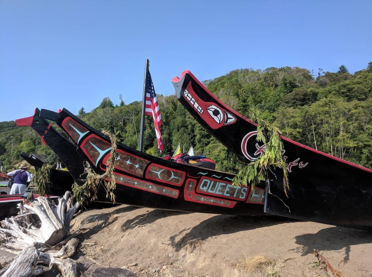 Tribal canoes rest on a shoreline.