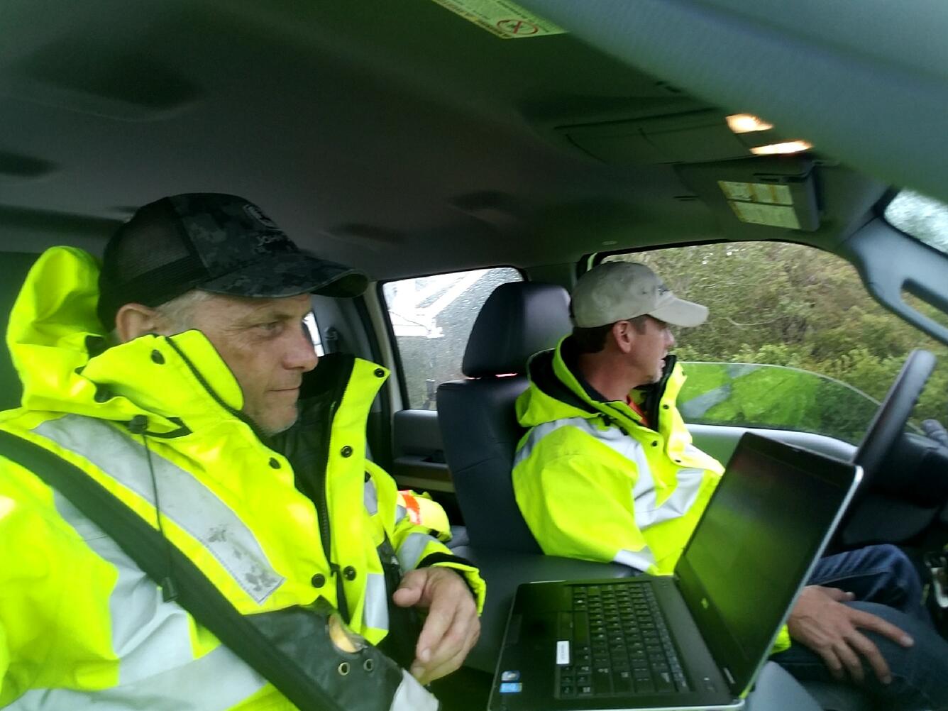 Image shows two USGS scientists in a truck, looking at a computer screen.