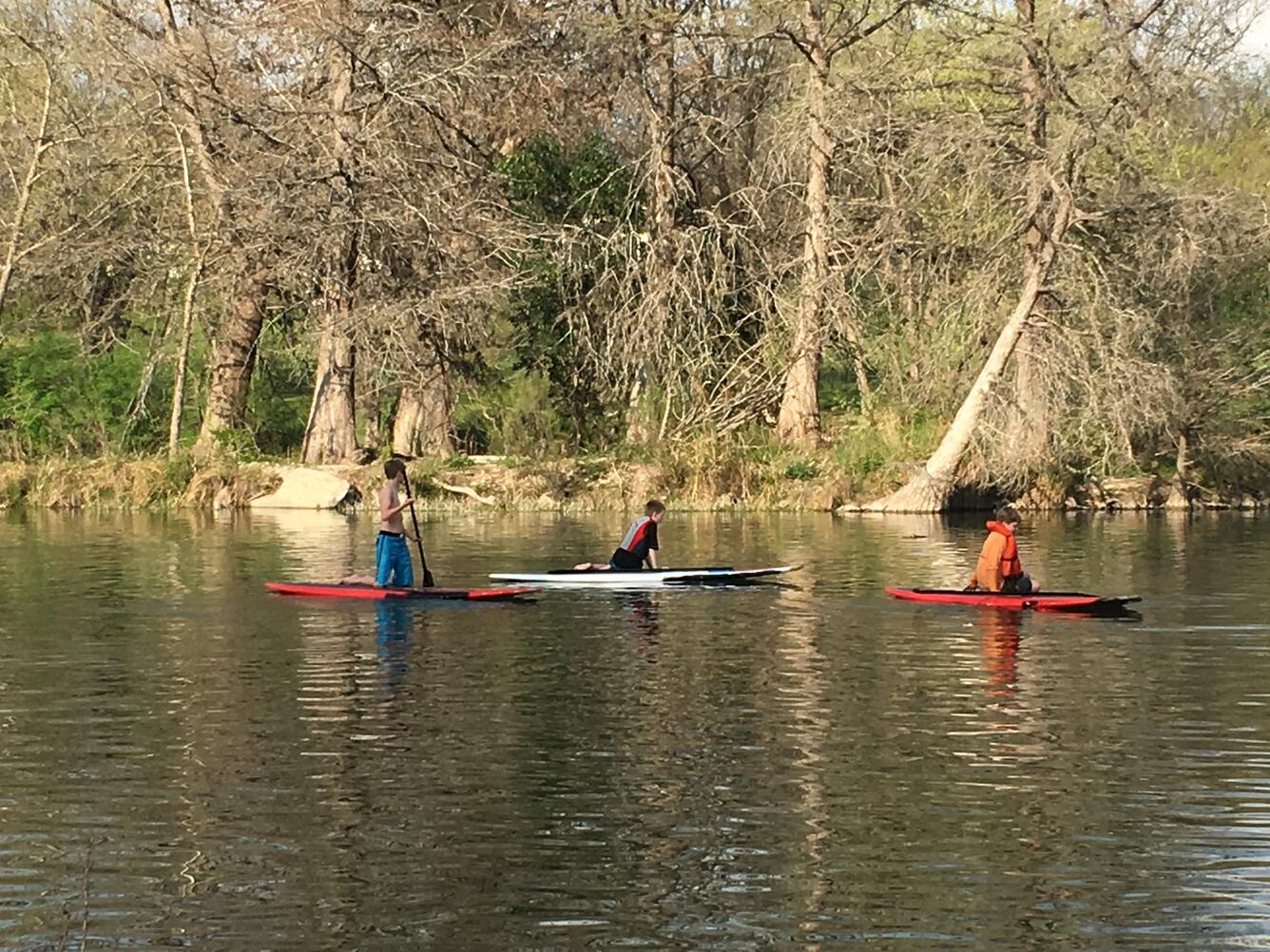 A family enjoys paddleboarding at Schreiner Park during spring break in Kerrville, Texas.