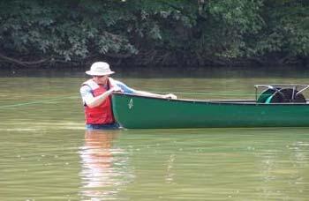Guided by a hydrologist ,in the water,a canoe was used to carry the reel of cable in the river.