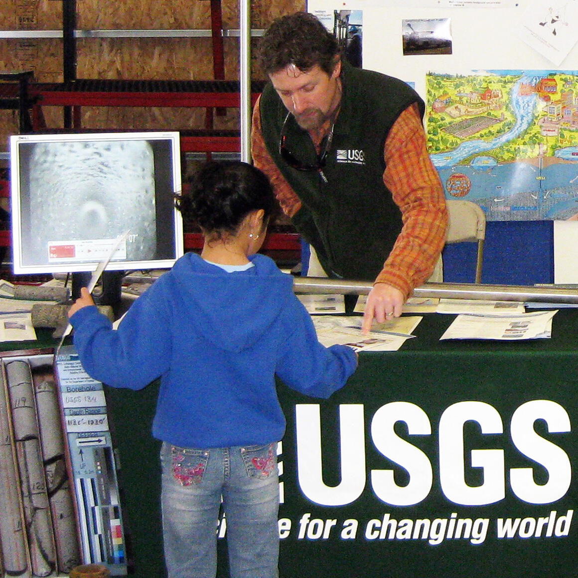 USGS scientist talking with a child at a public outreach event