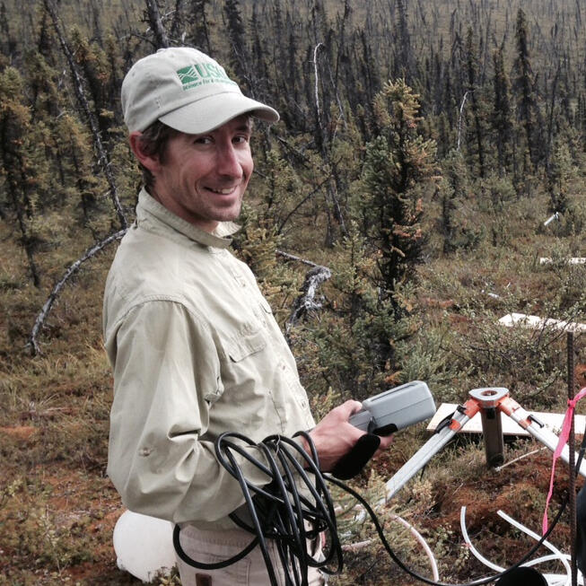 Josh Koch holding a subsurface tracer monitor on the West Twin Creek hillslope getting ready for a test