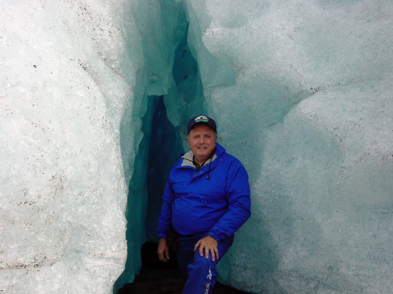 Bruce Molnia standing in front of the opening of a small ice cave 