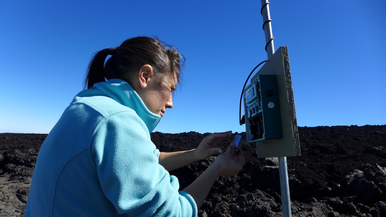 Zoologist changes the batteries of an acoustic monitoring device at the top of a mountain