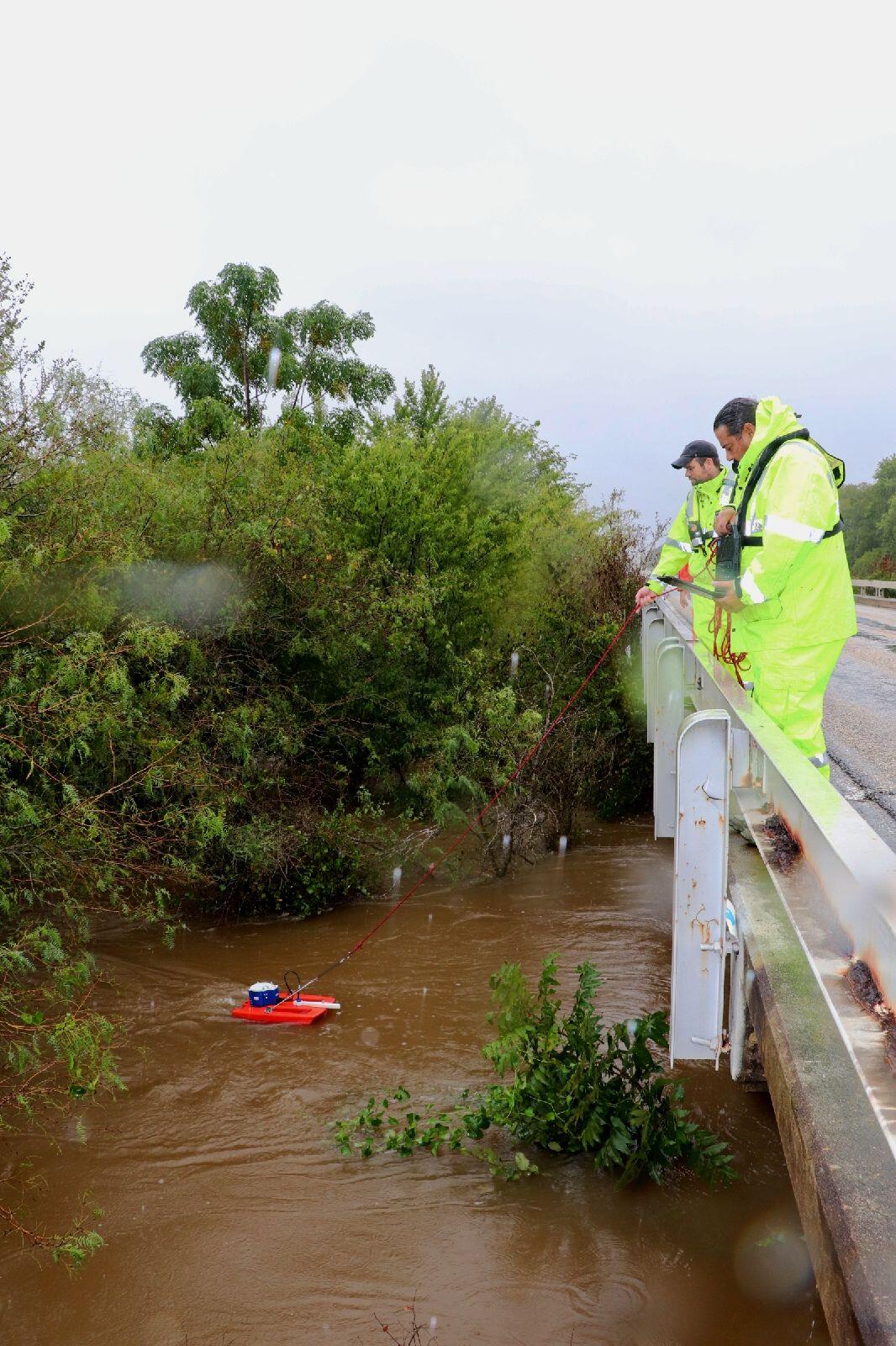 Image shows USGS scientists in PFDs with an acoustic doppler sensor in a flooded river