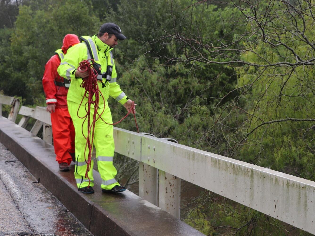 Image shows USGS scientists in PFDs measuring flooding along an elevated roadway