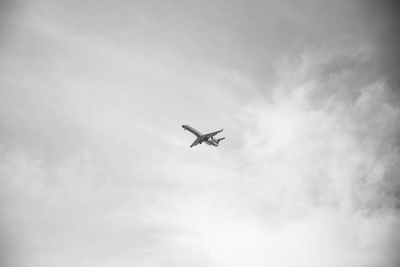 white plane flying over gray clouds