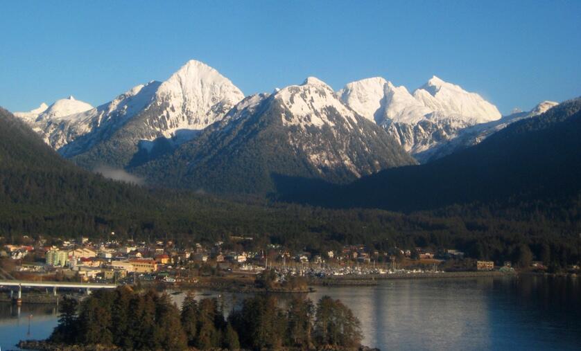 Sitka, AK, with mountain view just behind a lake in the area. A town sitting on the lakes edge.