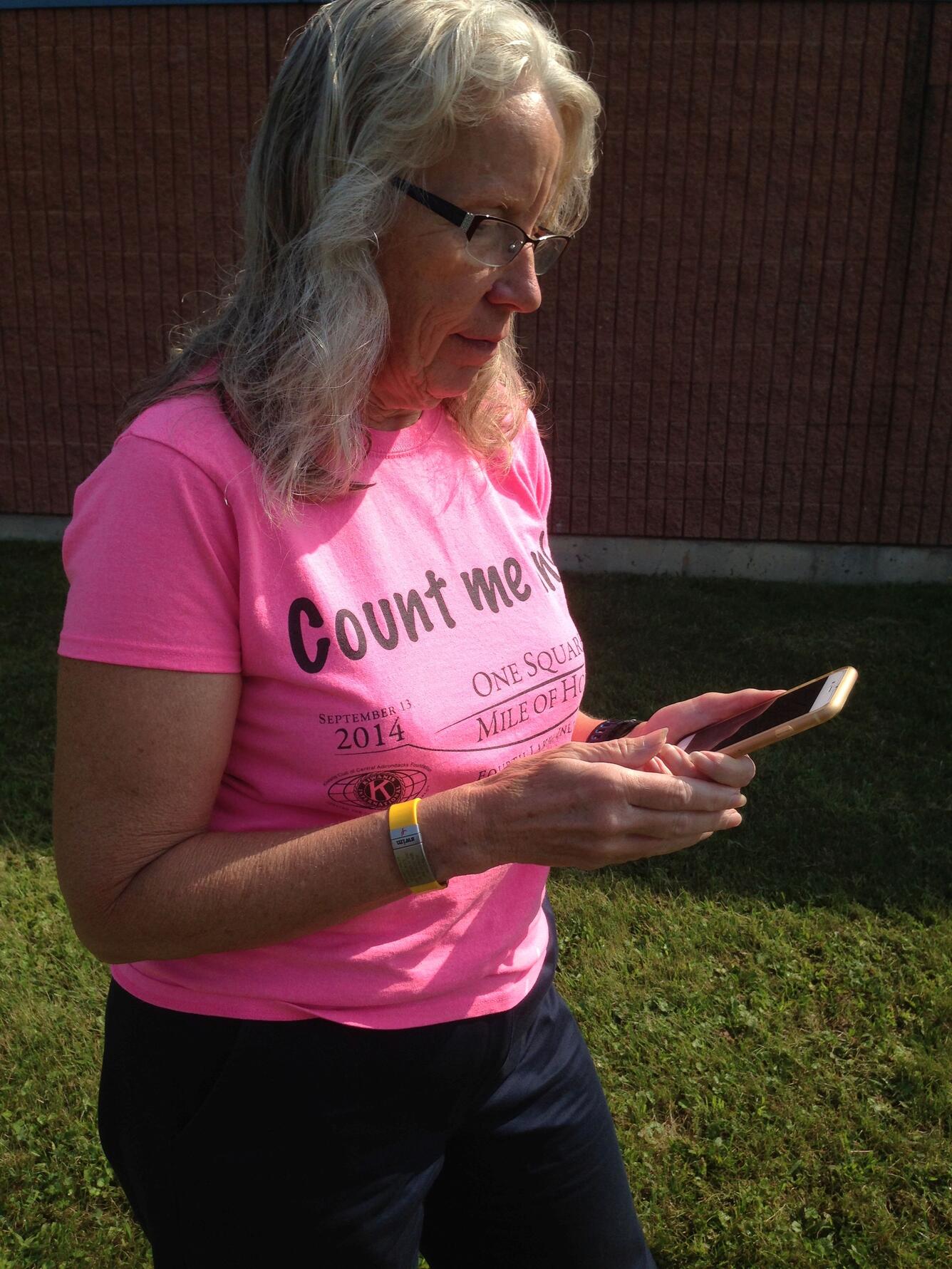 woman in pink shirt looking at cellphone