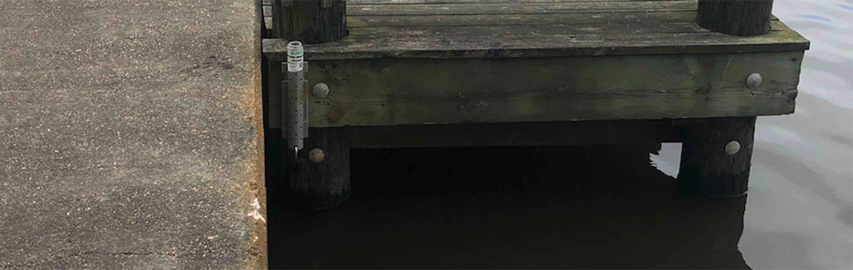 An image showing a storm tide sensor in a metal casing attached to a pier. 