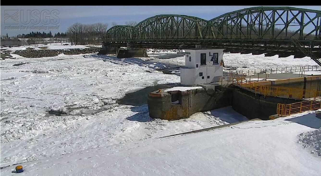 white ice and snow on river by train bridge