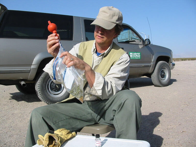 A USGS scientists collecting a sample from a plastic bag with a pipet