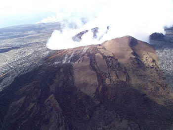 Aerial view to the south shows a fuming Pu`u `O`o vent with the East Kamokuna ocean-entry steam plume visible in the background