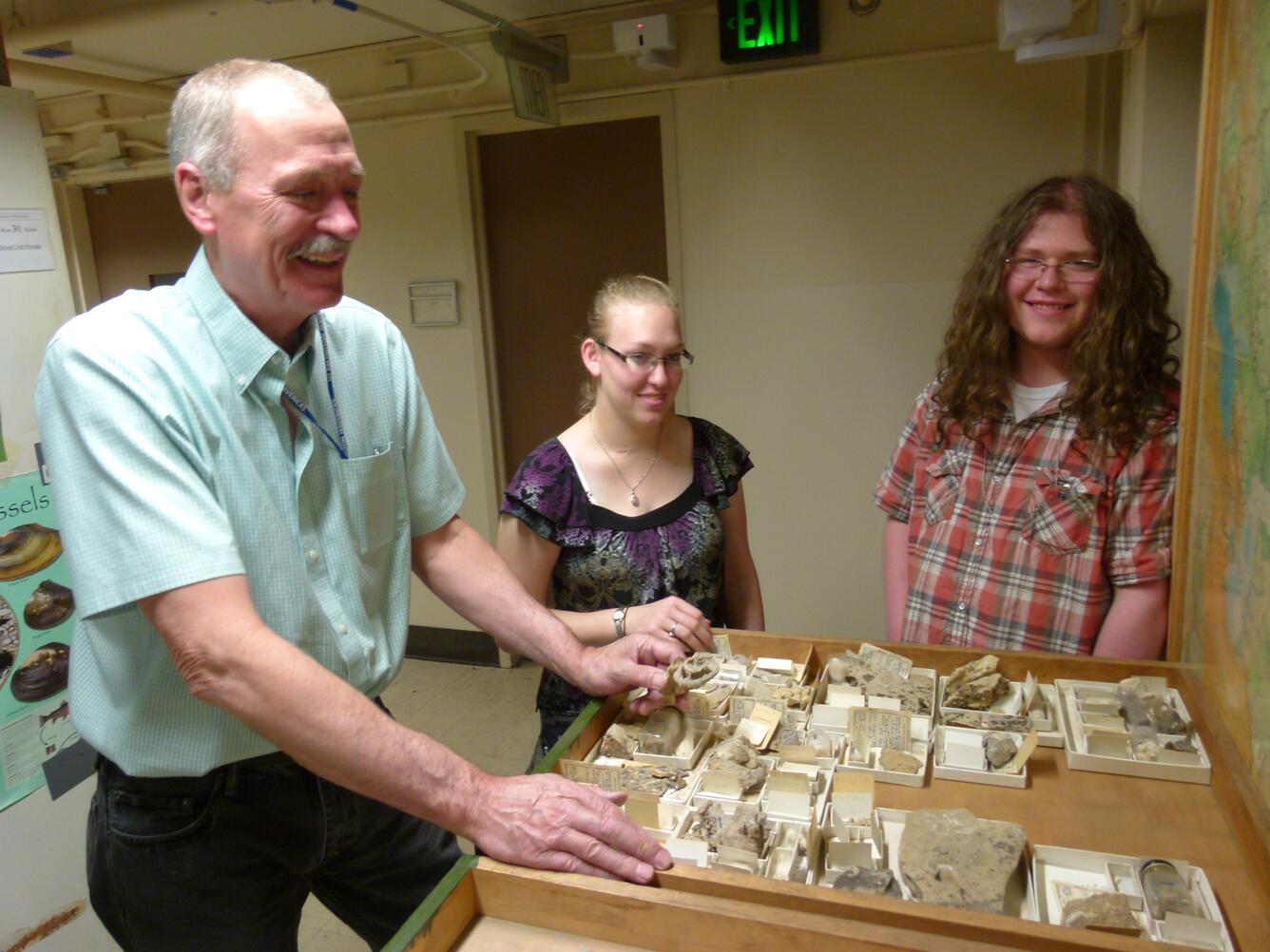 USGS scientist Bruce Wardlaw working with student volunteers on a tray of fossil specimens.
