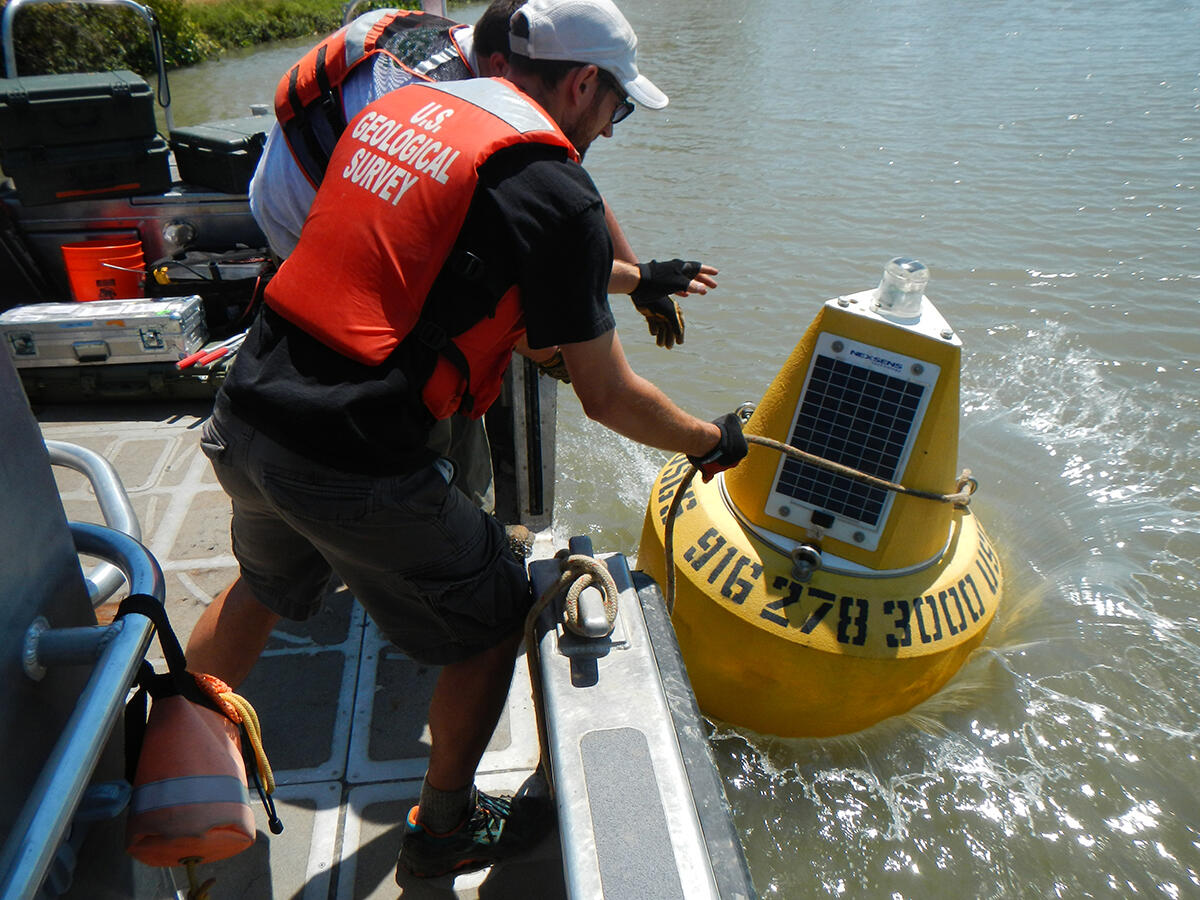 hydrologists launching water quality buoy