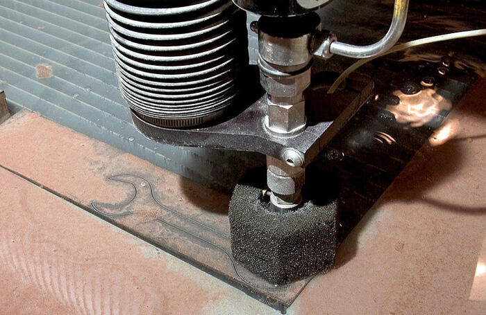 Waterjet pressure cutter cutting out a tool from metal.