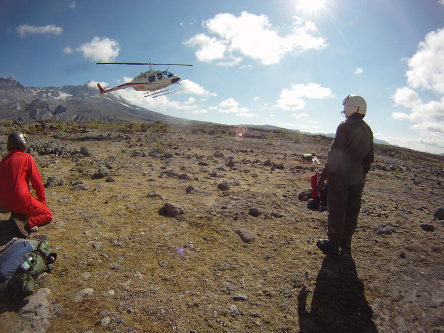 Scientists wait for helicopter pick-up on the remote Pumice Plain, ...