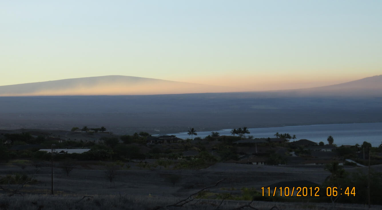 The summit of Mauna Loa (left) rises above the vog layer on the lee...